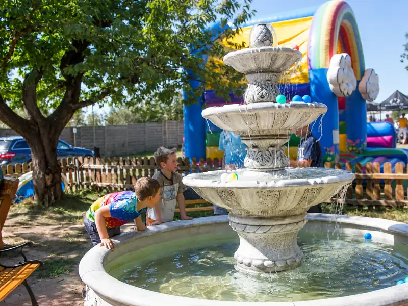 Zwei Kinder spielen am Springbrunnen im Hof, dahinter eine Hüpfburg