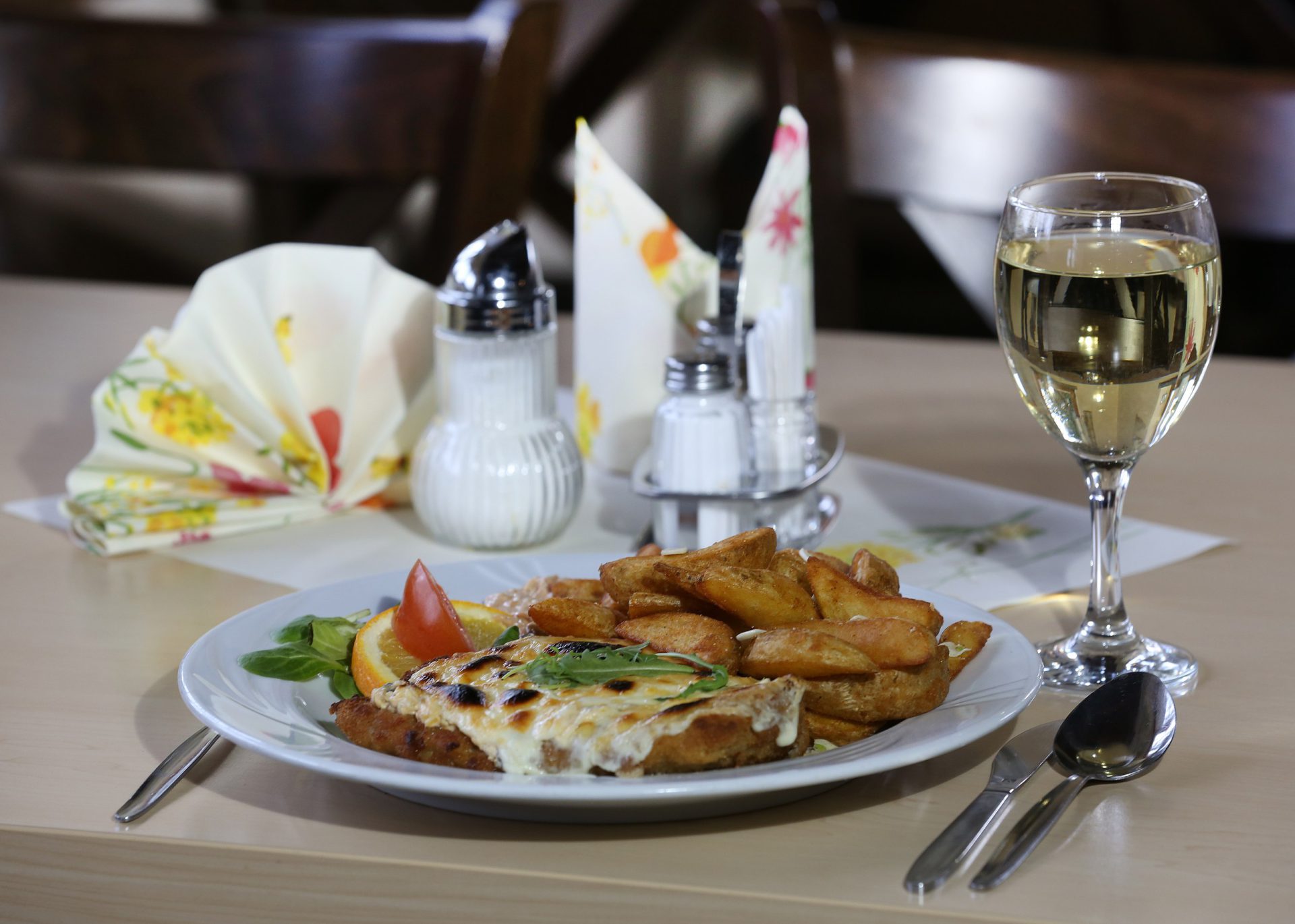 Überbackenes Schnitzel mit Kartoffelspalten und Weißwein